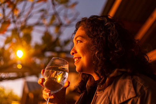 Latin woman with glass of water looking at sunset