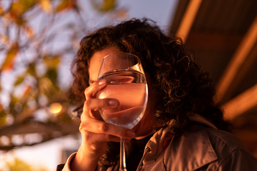 Latin woman with glass of water looking at sunset