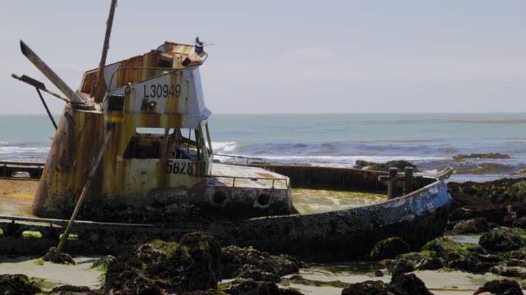 ABANDONED FISHING VESSEL, OM THE ROCKS, AT LOW TIDE.  4K, NO PEOPLE.