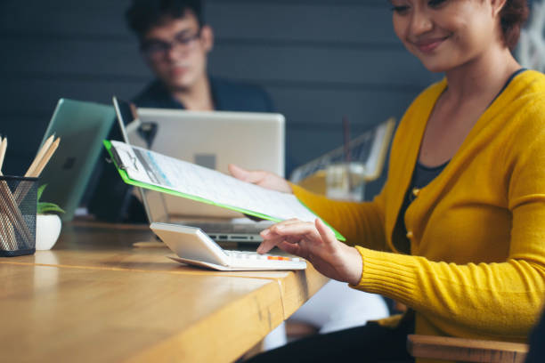 concetto di pianificazione delle tasse e del budget di stagione da pagare. donna d'affari felice che calcola l'imposta annuale e utilizza la calcolatrice. laptop, rapporto annuale sull'imposta sul reddito personale posto sulla scrivania dell'ufficio di cas - individual event women adult professional occupation foto e immagini stock