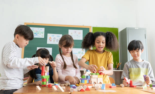 alumnos de escuela primaria multiétnica jugando juguetes de bloques de madera - 8 9 años fotografías e imágenes de stock