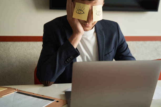istock Office employee pretending to work with eye stickers on face 1402914366