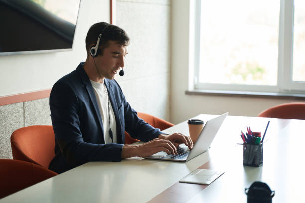 istock Worker conducting online-business through laptop and headset 1402915148
