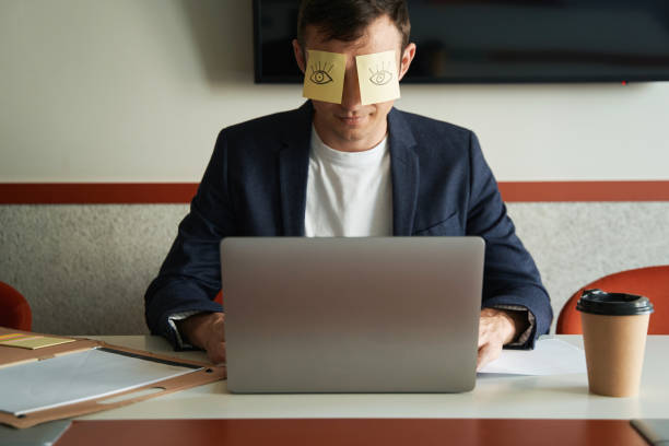 istock Male working on laptop with sitckers on his eyes 1402915176