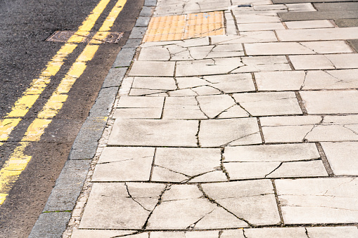 Paving stones on a British street badly damaged by vehicles using the pavement.