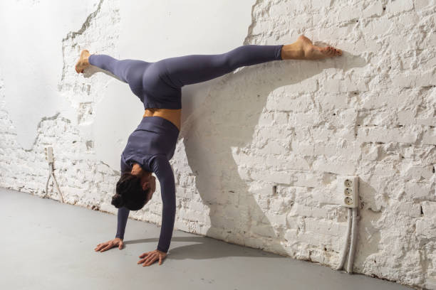 istock A female yoga practitioner performs the Adho Mukha Vrikshasana exercise with Samakonasana, two handstand with cross splits near a brick wall 1402915551