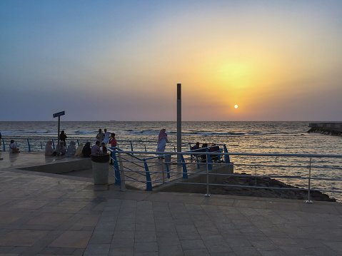 Jeddah, Saudi Arabia - April 7, 2015: View of people and families hanging out, walking and having a picnic, along the Jeddah's corniche by the Red Sea, before sunset.