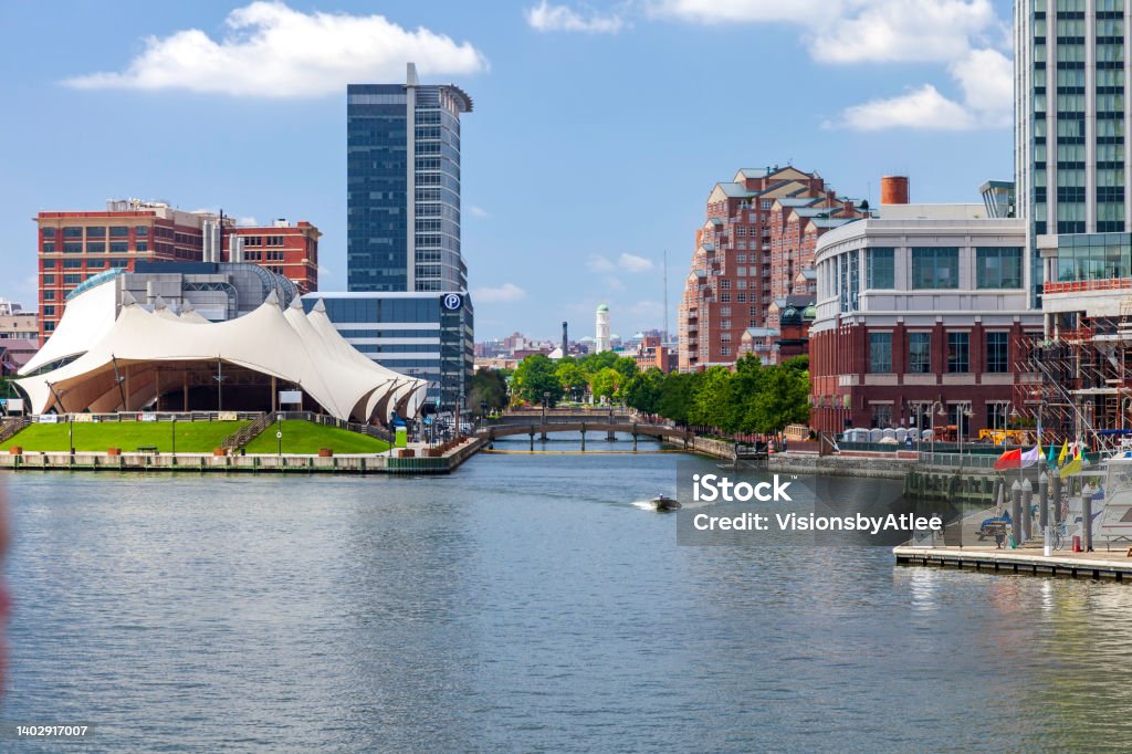 Pier Six Concert Pavilion alongside the  treelined Jones Falls channel at Baltimore Inner Harbor with museums and other attractions plus residential structures on the other side of the canal Baltimore - Maryland Stock Photo