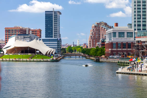 Pier Six Concert Pavilion alongside the  treelined Jones Falls channel at Baltimore Inner Harbor with museums and other attractions plus residential structures on the other side of the canal stock photo