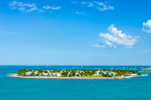 Luxury homes on a palm tree covered island next to Key West Florida with a private pier and is  surrounded by pleasure boats and beautiful turquoise waters
