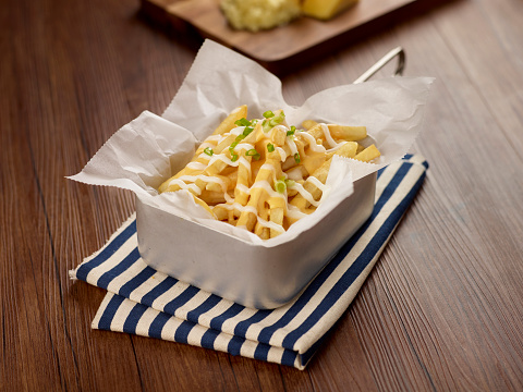 Cheese potato Fries in a dish isolated on napkin dark wooden table side view singapore food