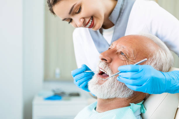 istock Female dentist with senior patient examining teeth 1402918760