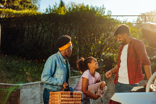 African happy family just arrived in the holiday cottage. They are checking do they take out everything from the trunk of the car