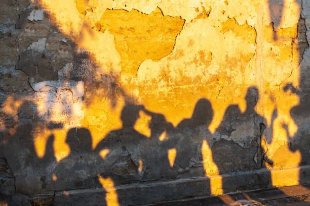 istock Shadows of dancing people on an old stone wall at sunset time. 1402920712