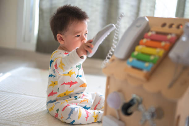 istock Baby boy playing with large activity box in the bedroom while sitting on a baby safe soft playmat on the floor at home. 10 months old infant playing at home 1402921858