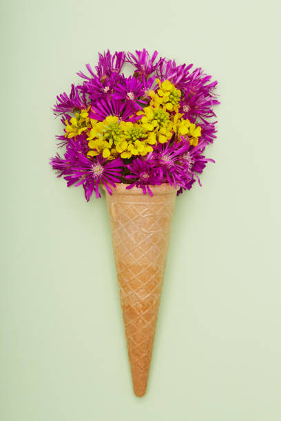 istock Fresh wildflowers in ice cream cone on green background flat lay 1402924739