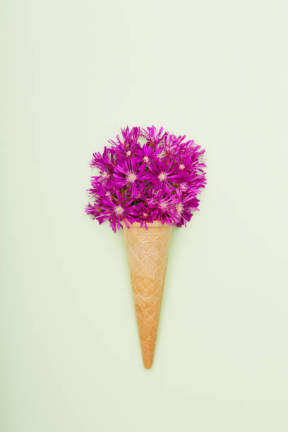 istock Fresh wildflowers in ice cream cone on green background flat lay 1402924886