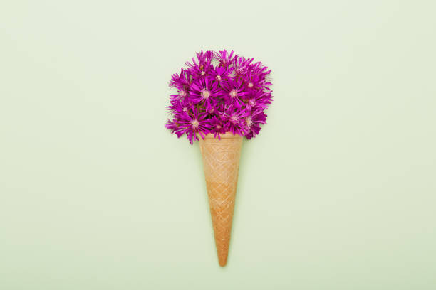 istock Fresh wildflowers in ice cream cone on green background flat lay 1402925080