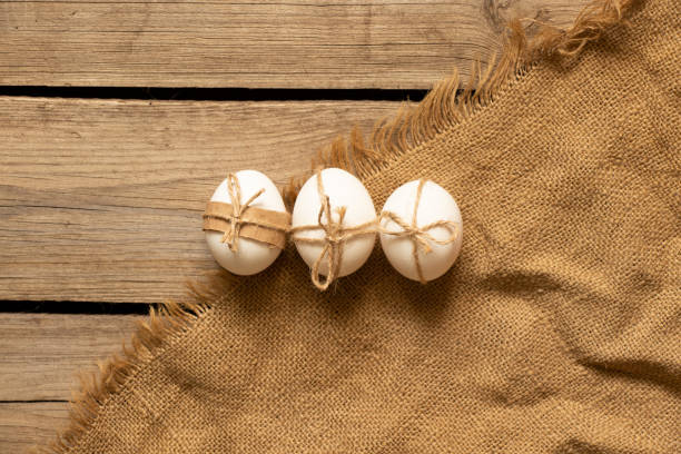 istock Chicken eggs tied with a rope lie on a wooden table on a tablecloth, Easter holiday 1402928933