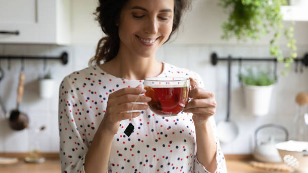 mujer feliz tomando un descanso para tomar el té, sosteniendo una taza de vidrio - tea drink cup afternoon tea fotografías e imágenes de stock