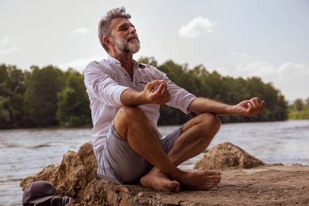 istock Senior man doing yoga exercise  in nature close river 1402937642