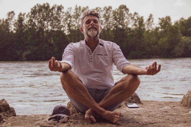 istock Senior man doing yoga exercise  in nature close river 1402937651