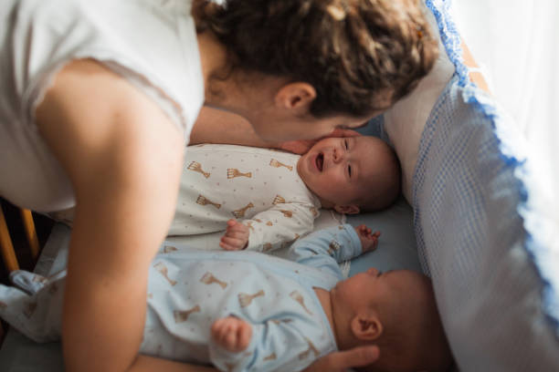 istock Woman cuddling her cheerful twin babies 1402941668