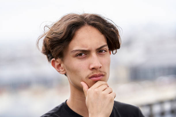 Portrait of a teenage boy looking at camera with brooding expression and hand on chin