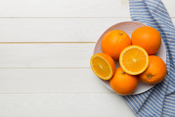 istock Flat lay of Fresh orange fruit with sliced in plate on Colored background. Top view with copy space 1402942402