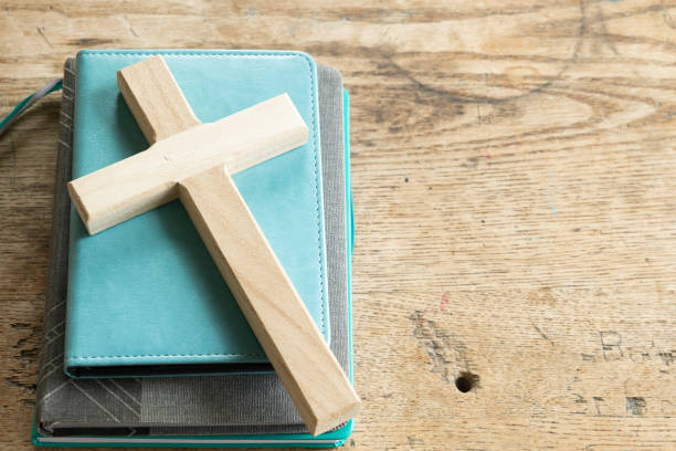 istock Wood cross on stack of teal and grey books 1402943351