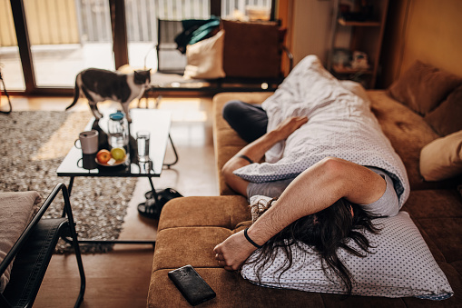 One man, young male sleeping on couch in his living room at home.