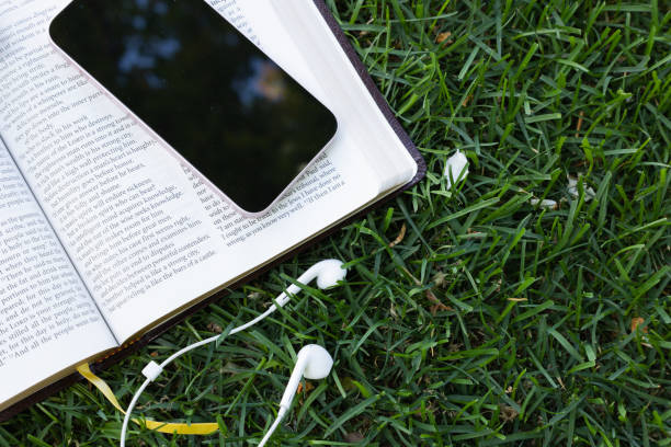Open bible with earbuds and device laying in the grass