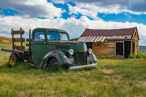 Old truck in field with rustic cabin