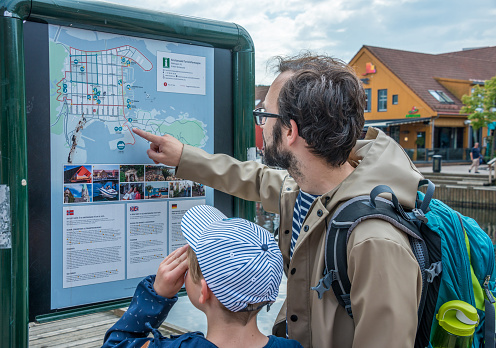 Kristiansand, Agder, Norway - August 08, 2018: Tourists consulting a map of the city in the port of the Fish Market