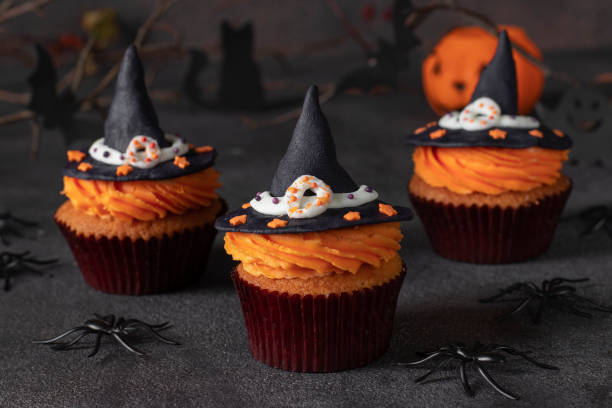 istock Halloween cupcakes decorated witch hat from mastic on gray background with spiders and bats. Sweets for kids on Halloween party 1402946071