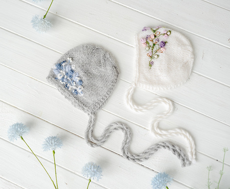 Handmade knitted hats set for newborn studio photoshoot decorated with flowers. Infant accessory wear