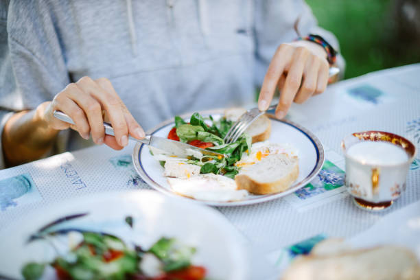 Outdoor eating, friends having breakfast together on a table set in the beautiful sunny nature.
