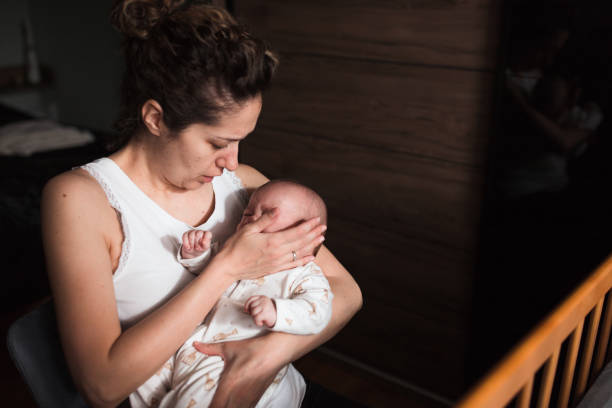 Concerned woman holding crying newborn baby in her arms stock photo