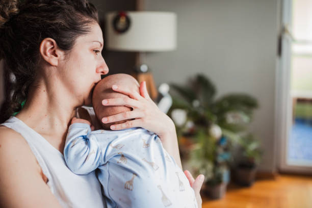 Woman kissing her baby's head stock photo