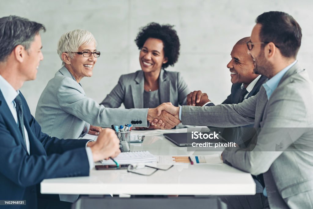 Businesswoman and businessman shaking hands across the table Business persons shaking hands on a meeting Business Meeting Stock Photo