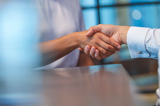 Close up of a Business man and woman shaking hands in the office.