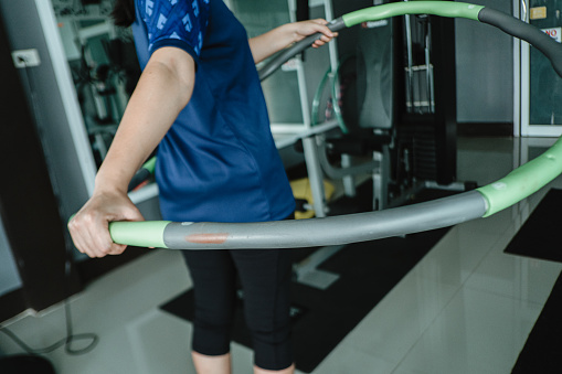 woman is exercising with Hula hoop in fitness gym for healthy lifestyle concept.