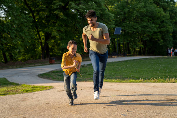 Father helping his son stretch on a dirt road in the forest