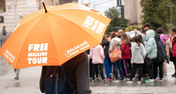Tour guide under orange umbrella with Free walking tour sign, on a city square stock photo