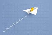 istock Paper airplane with gold coin is flying over grid of business graph 1402957805