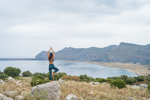 She flows into tree pose, Mediterranean Sea in the distance