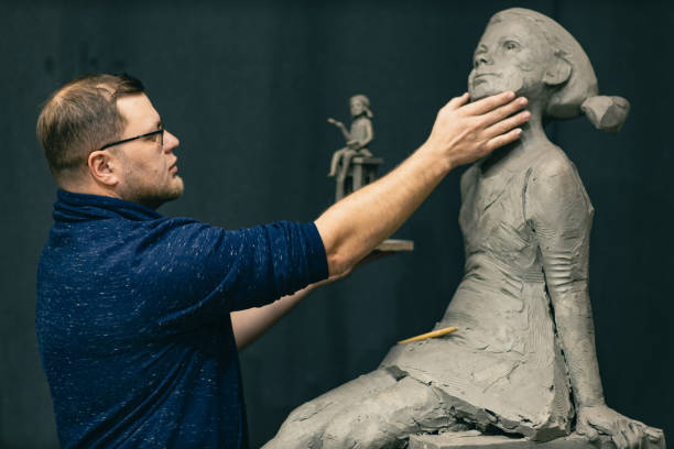 istock Man sculptor creates sculpt bust clay human woman sculpture. Statue craft creation workshop 1402962631