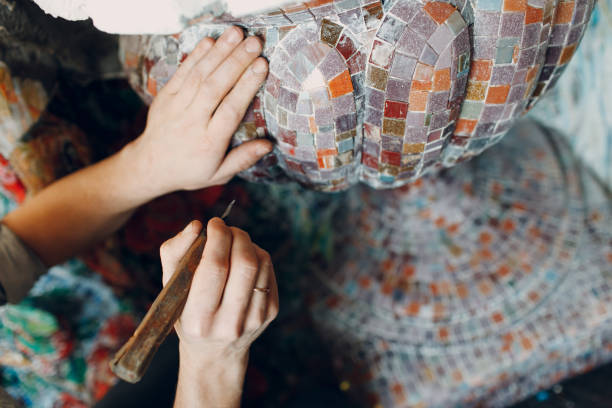 Man mosaics master in hat making smalt glass mosaic panel.