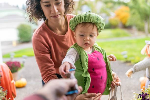 Adorable toddler trick or treating with her mom stock photo