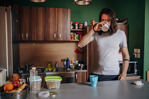 One man, young male drinking morning coffee in his kitchen at home.